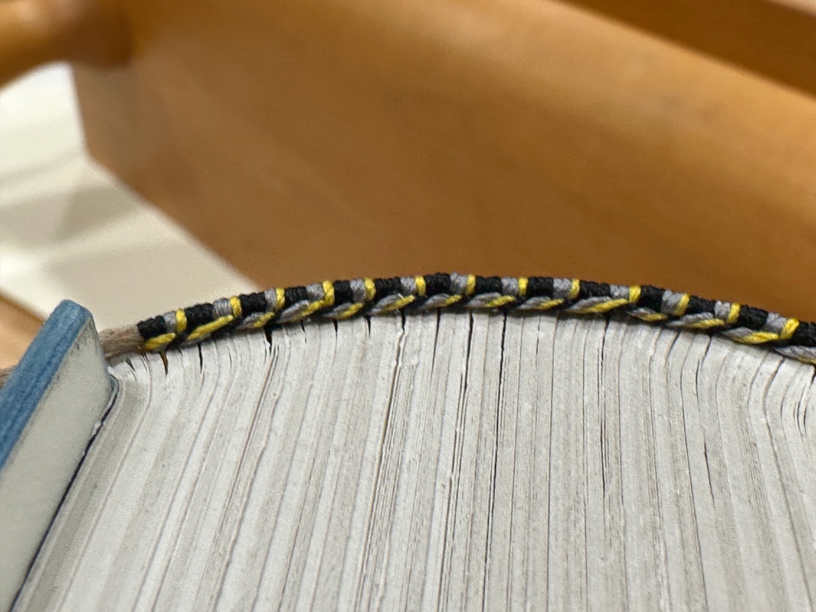 a close-up top of a book showing the hand-sewn black and gold end bands