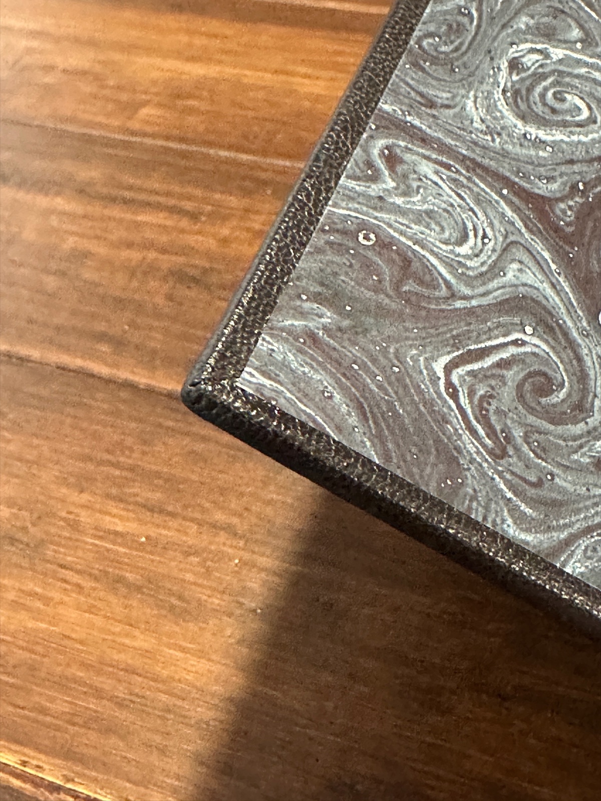 A close-up of the inside cover of the black leather book revealing the decorative black marbled paper