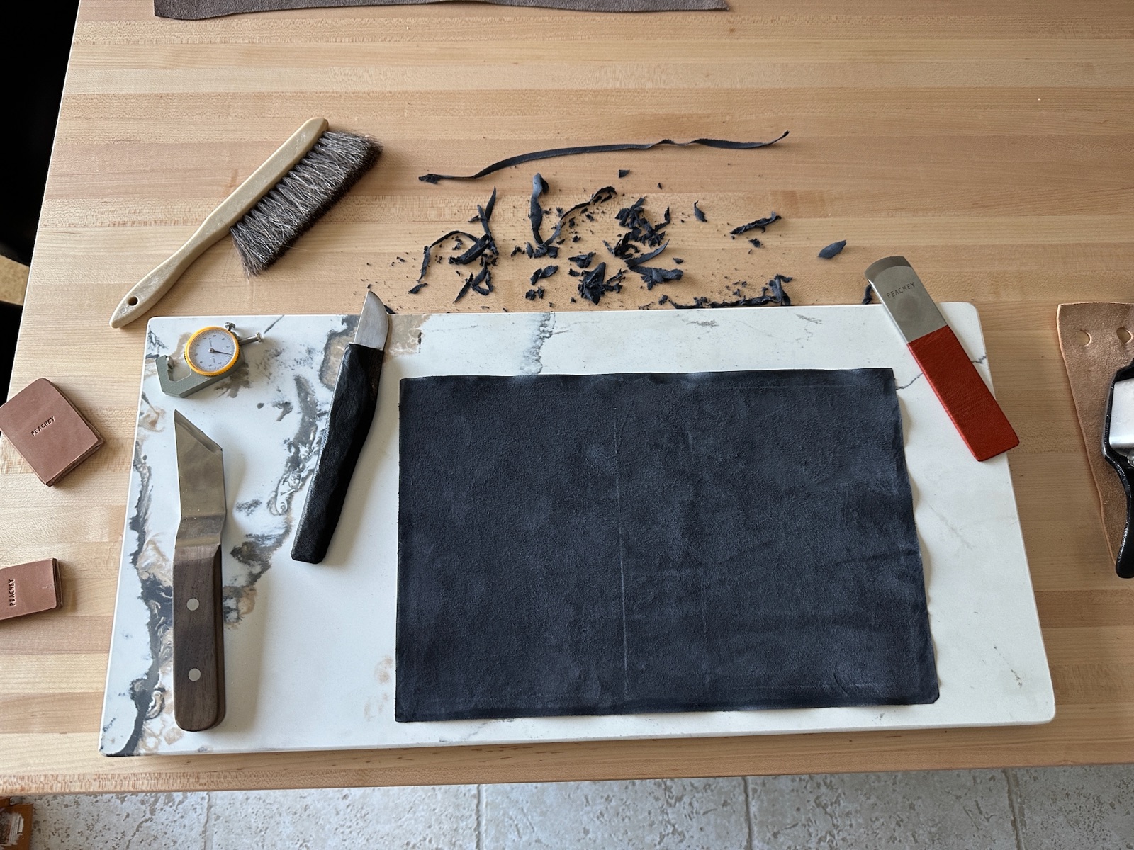 Black leather and tools on a workbench ready for paring the leather