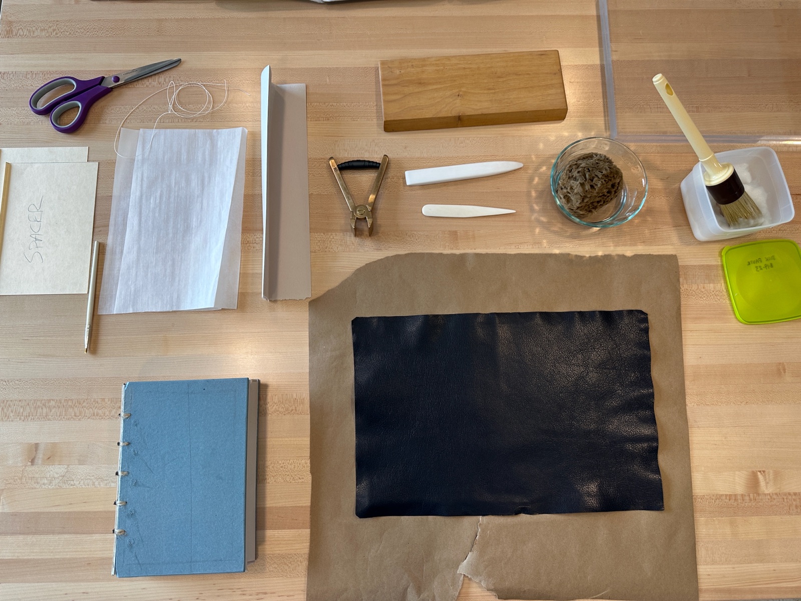 Black leather and tools ready for adhering the leather to the book
