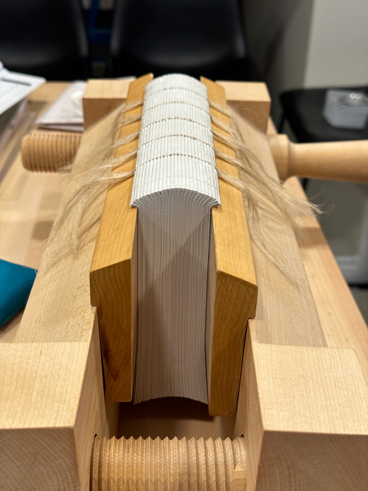 a text block in a standing press being rounded and backed.