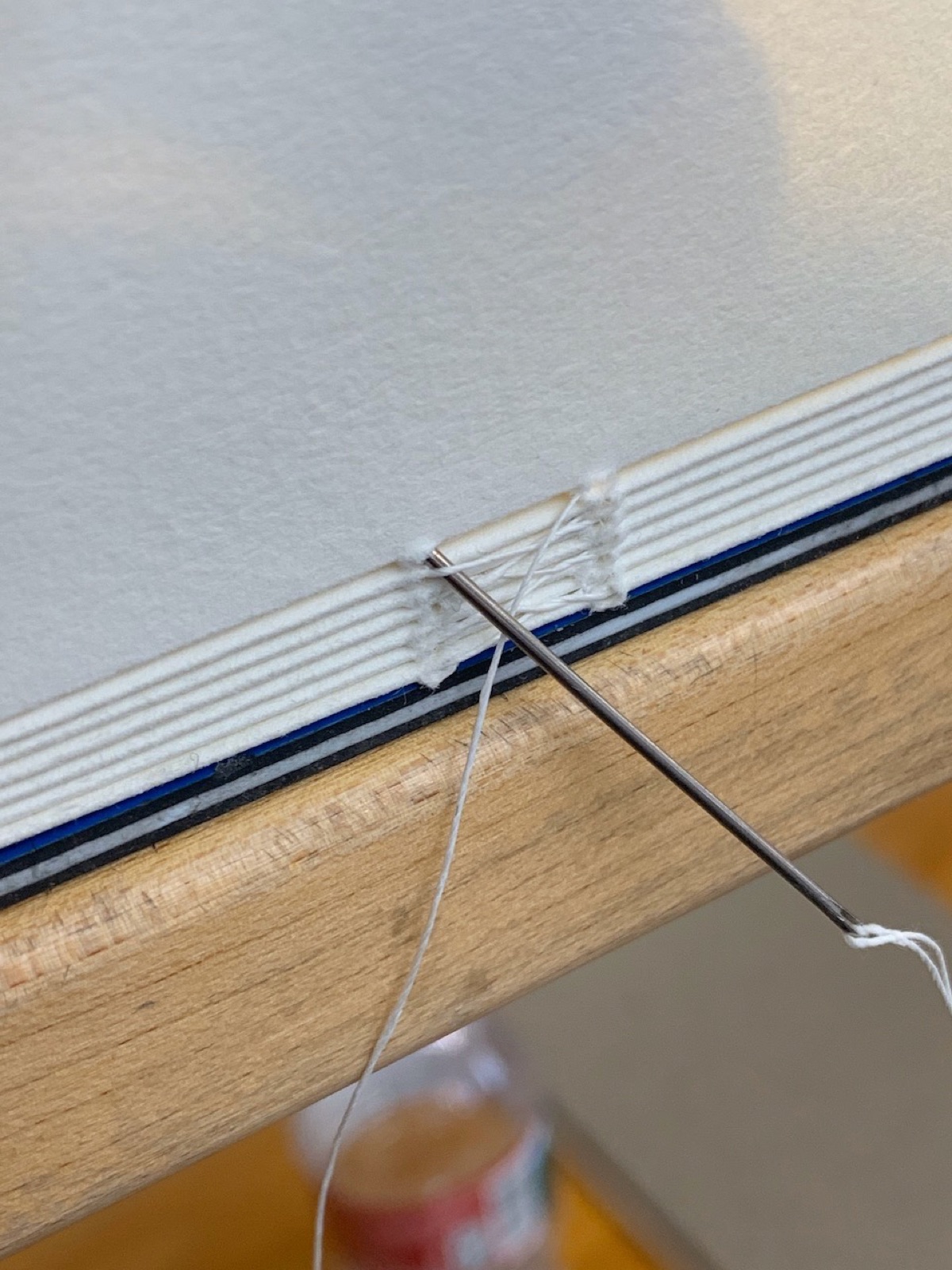Close up of text block being sewn with a large sewing needle