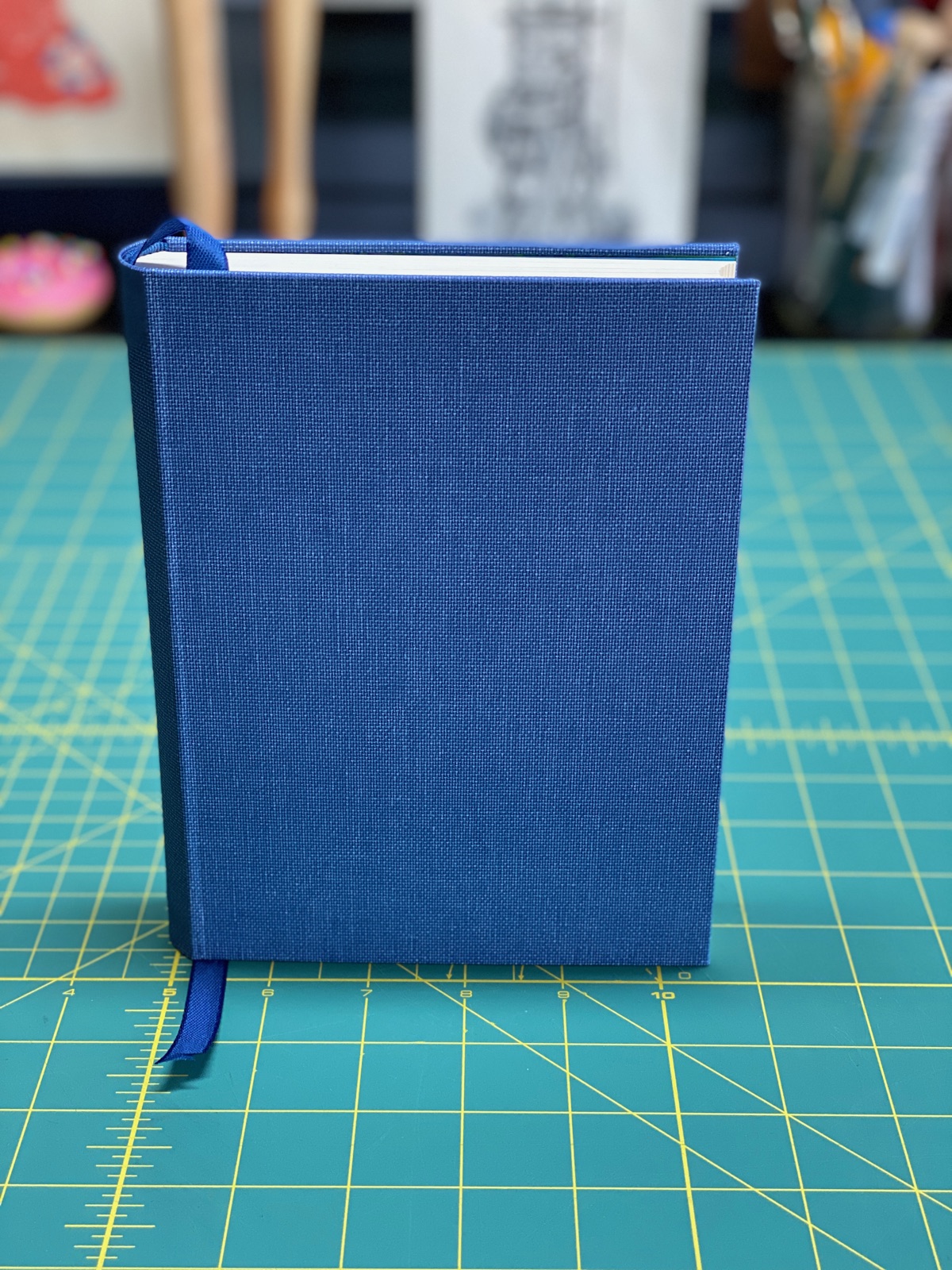 A blue cloth book standing on a crafting mat