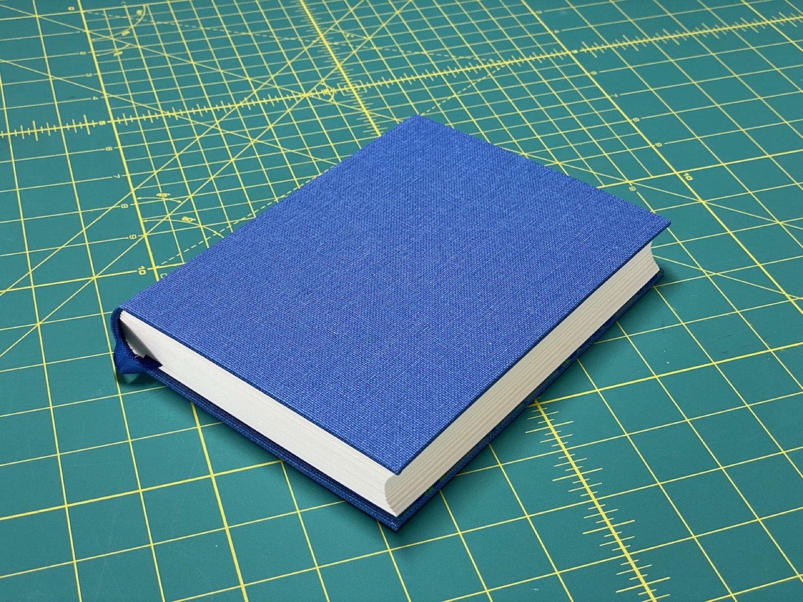 A blue cloth binding lying on a cutting mat.