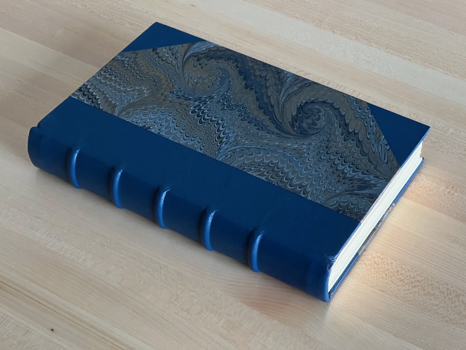 A binding with blue leather spine, raised bands, and patterned paper sides.
