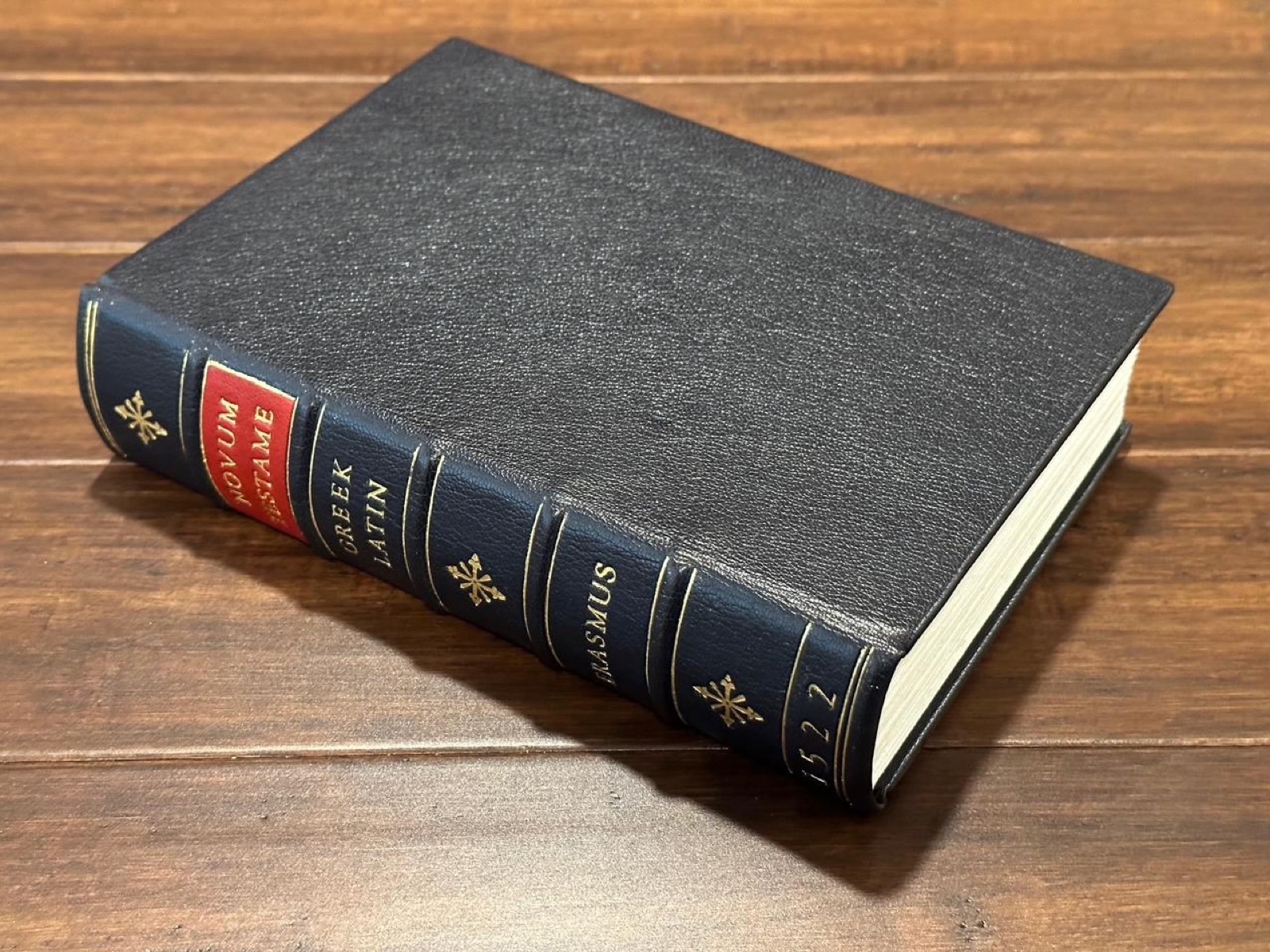 The finished 1522 Erasmus facsimile: a black leather binding with a gold-tooled spine on a wooden table.