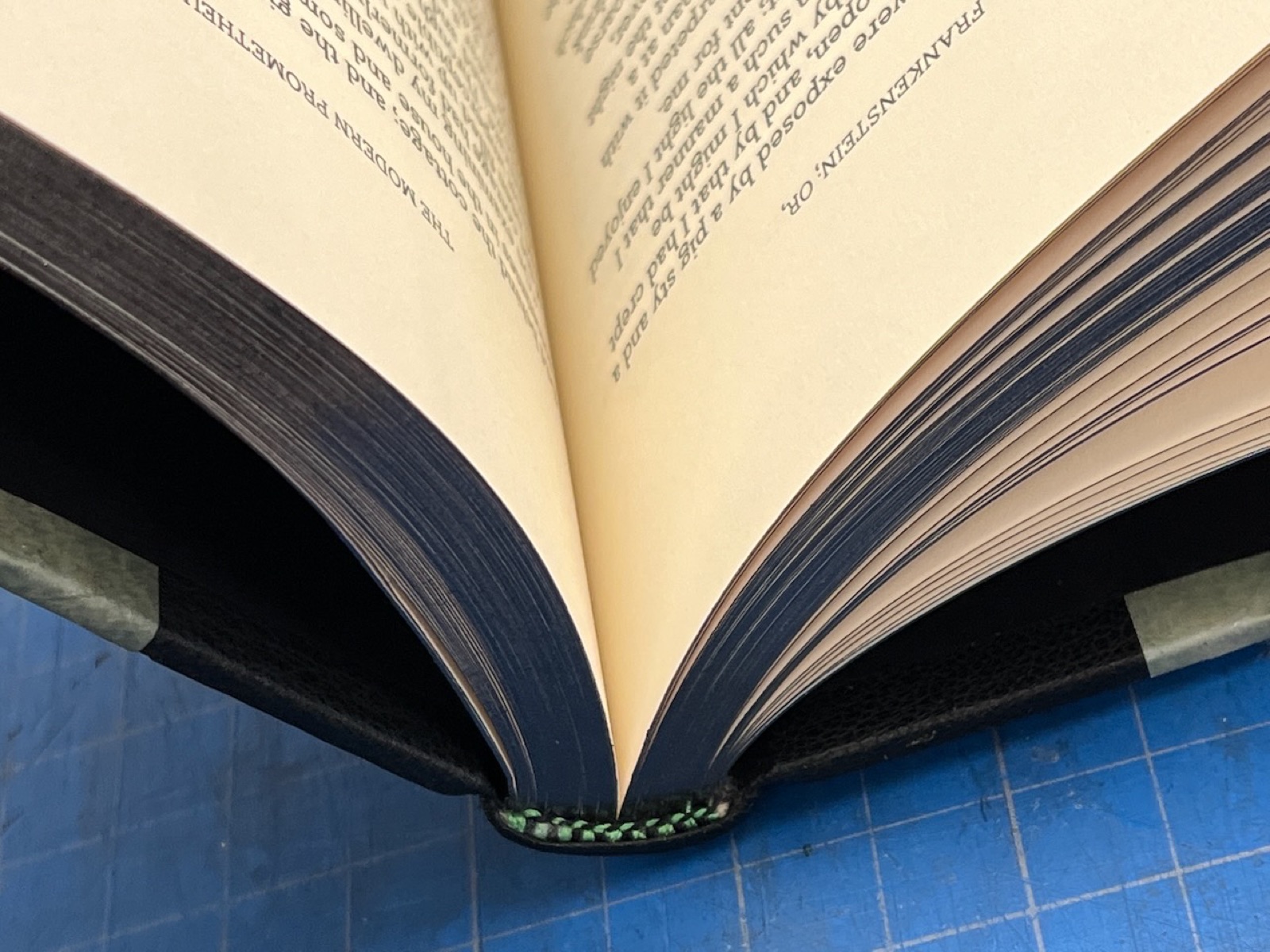 Close up of a spine of a book resting on a table with the book open