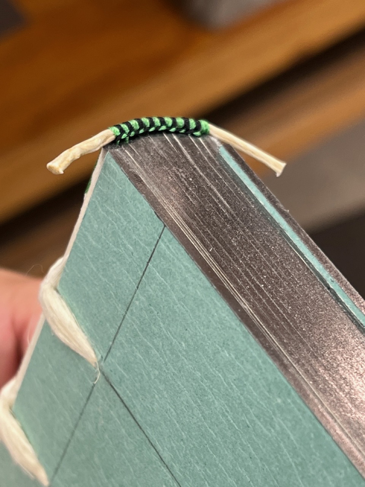 A book being held showing a completed green and black end band.