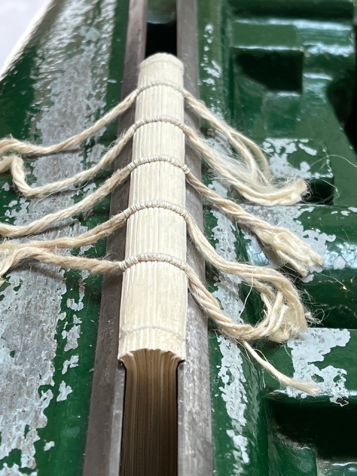 Text block spine-up in a backing press being routed and backed.