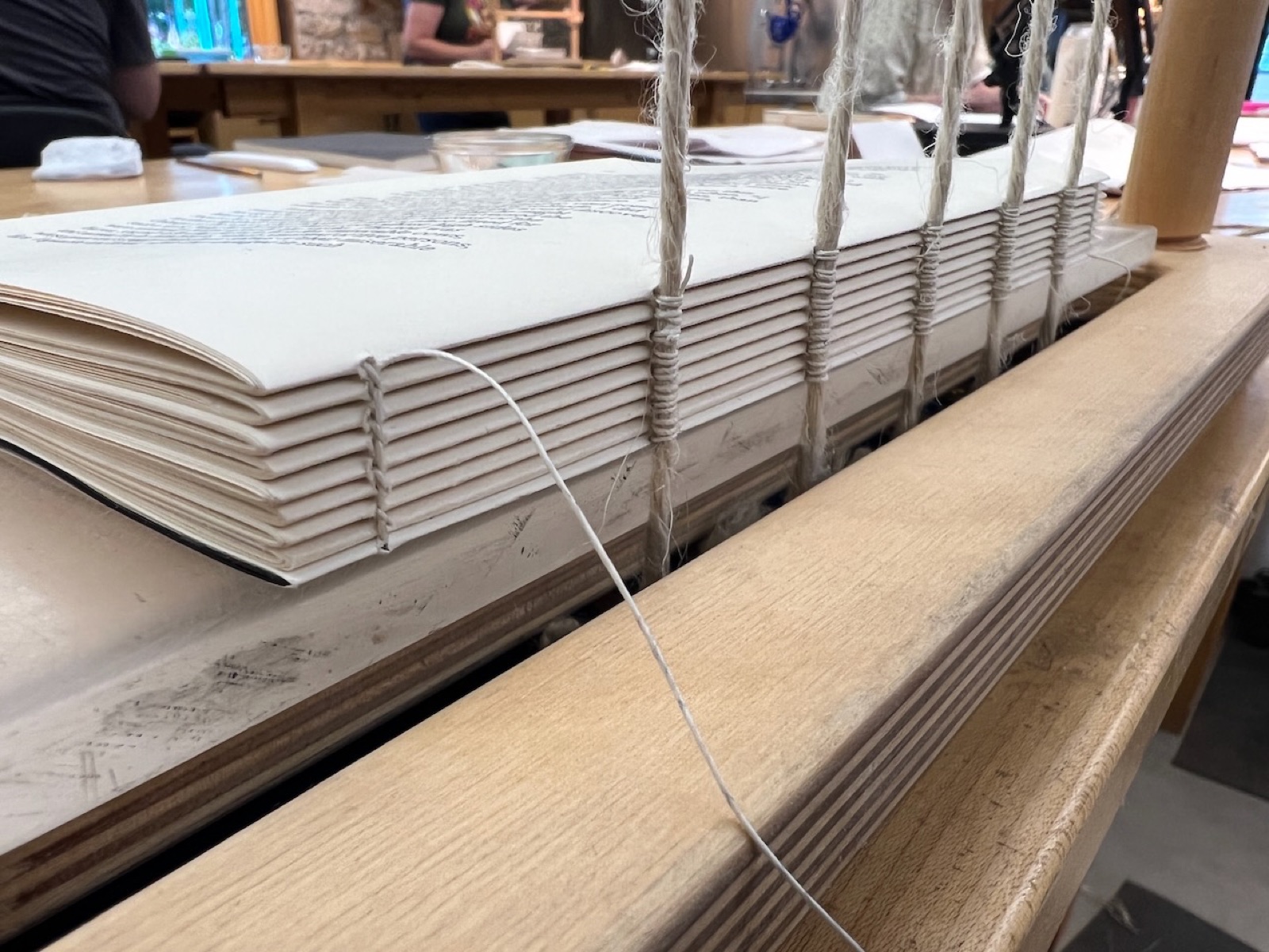 Text block in sewing frame with white thread around cords.