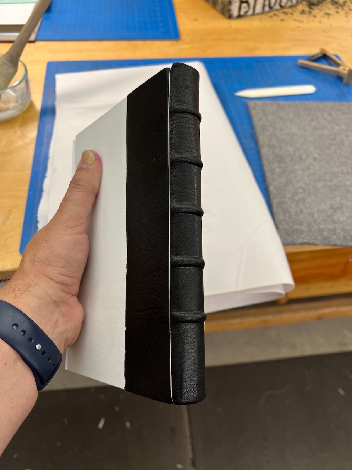 A book being held showing black leather adhered to spine.