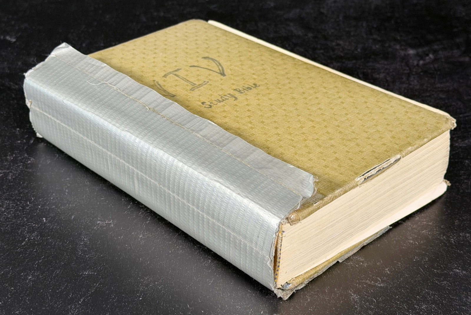 The Bible before treatment, closed, its spine and boards wrapped in silver duct tape.
