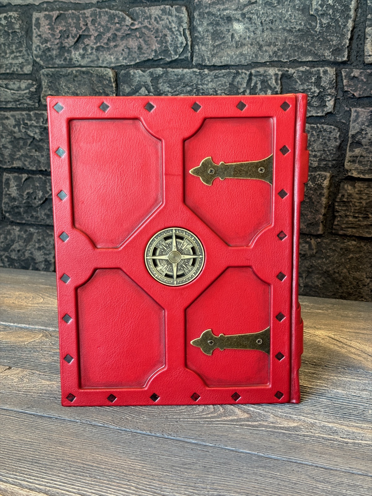 the back cover of the pirate bible showing red leather, black tooled areas and metal embellishments