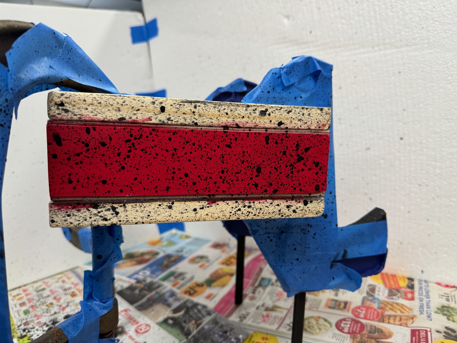 red painted and black speckled edges of a book in clamps