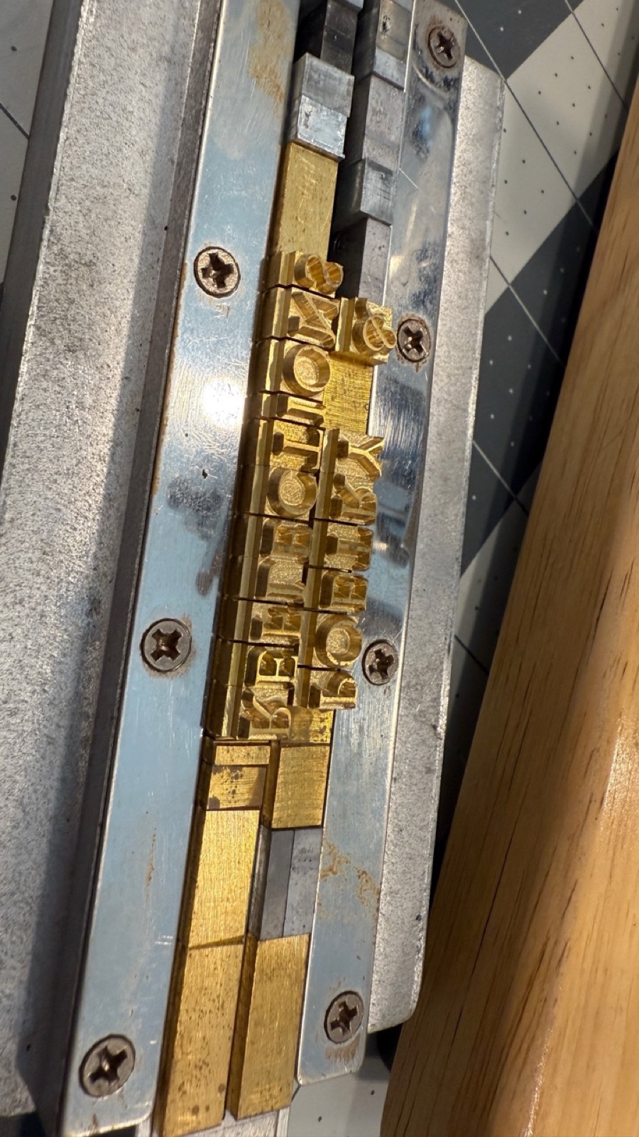 Brass letters spelling Poetry and Reflections set backwards into a type holder.