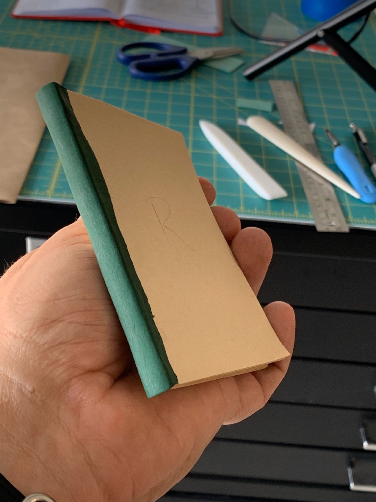 the primer in a binders hand showing the smooth green leather spine