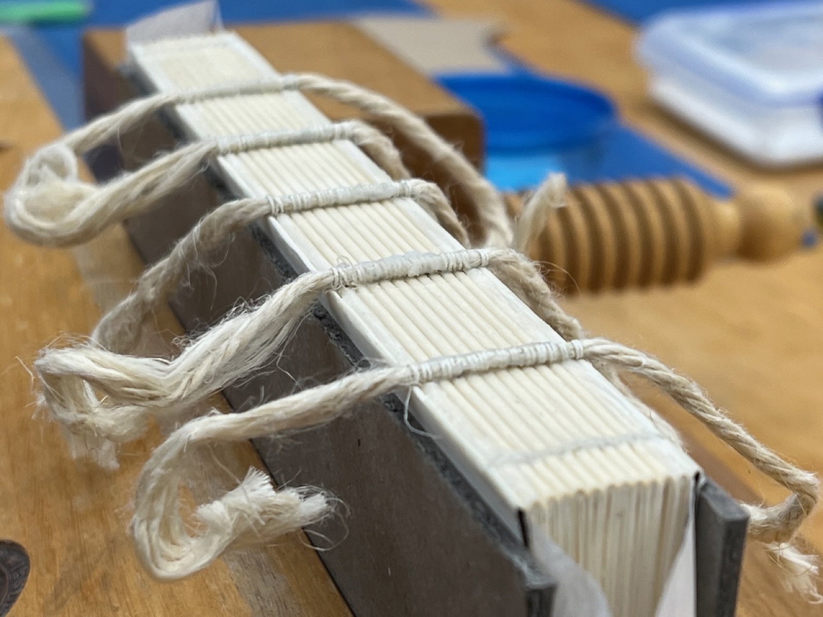 A sewn text block with cord sewing supports resting on a workbench.