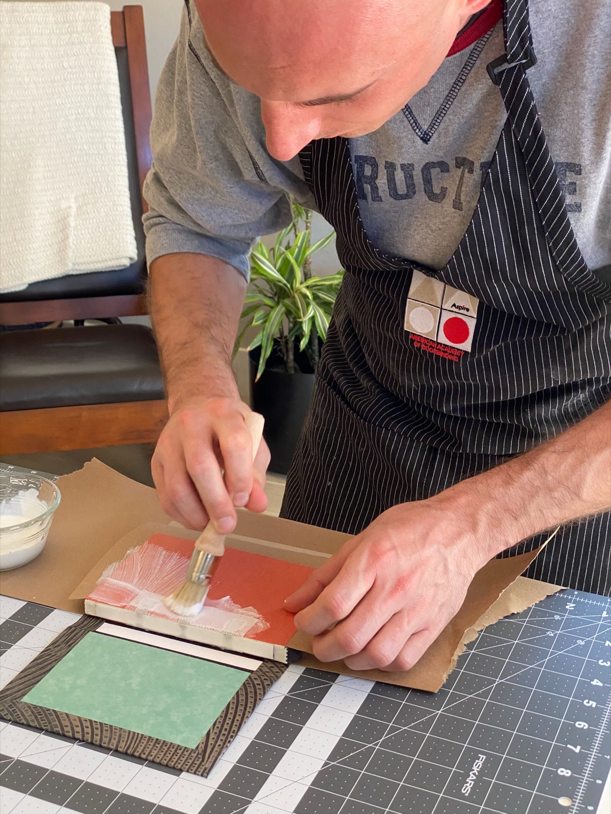 a person glueing the paper of a text block to case-in the book