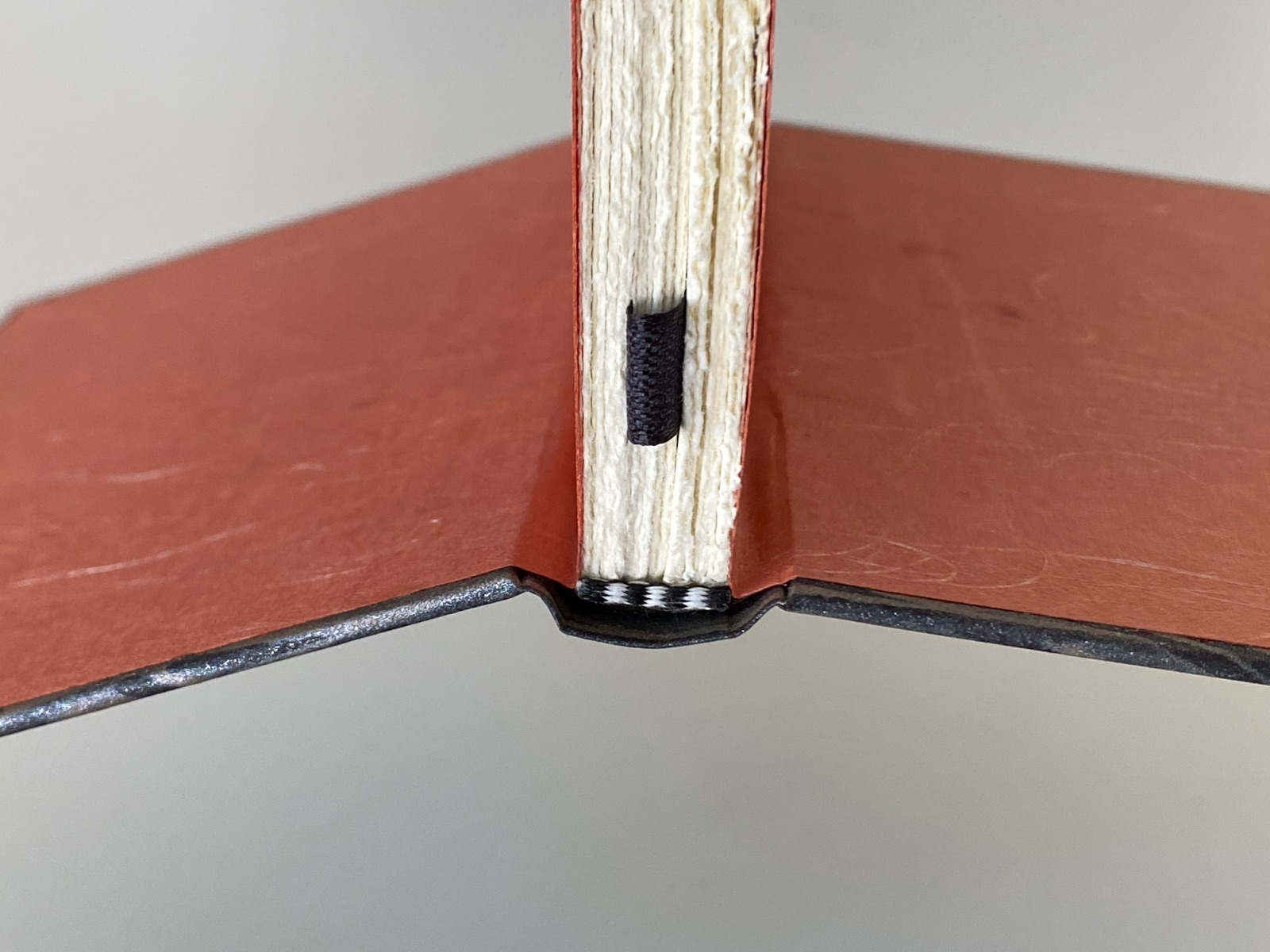 a completed close up of a notebook showing glued on end bands and a black silk ribbon bookmark