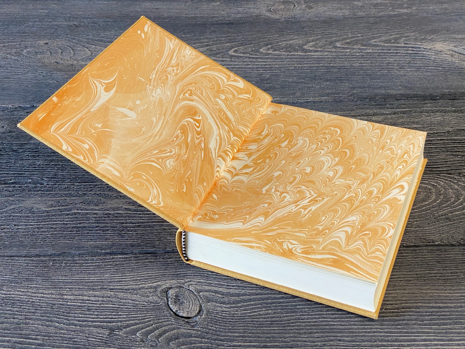 The finished yellow cloth book opened to reveal decorative yellow marbled paper