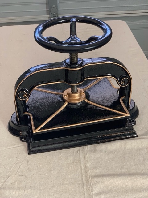 A restored antique cast-iron book press with brass details.
