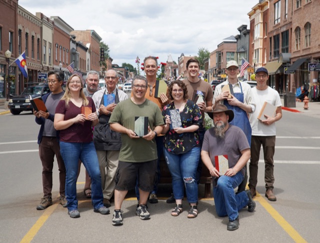 Bookbinding classmates holding finished books on the main street of Telluride, Colorado.