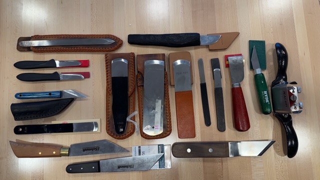 Bookbinding and paring knives arranged on a wooden bench.