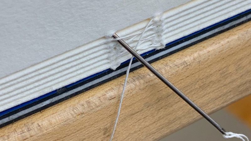 A spine being sewn with a link stitch that links the signatures to one another.