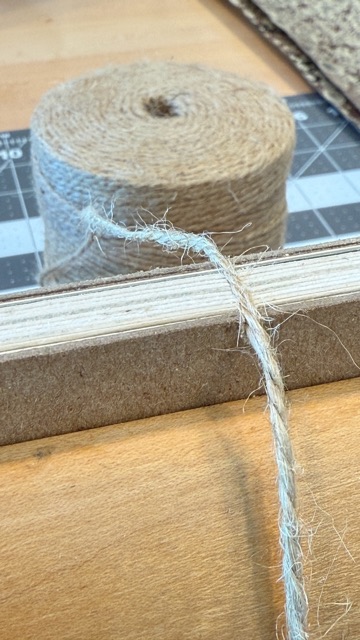 A roll of woven sewing tape beside board on a cutting mat.