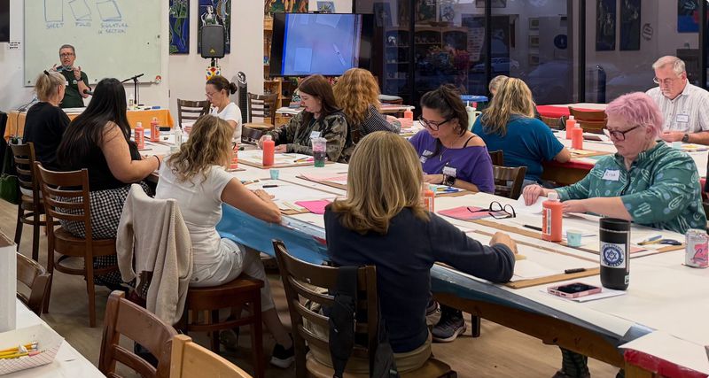 Students at work on their notebooks during the class, with Bob teaching at the front.