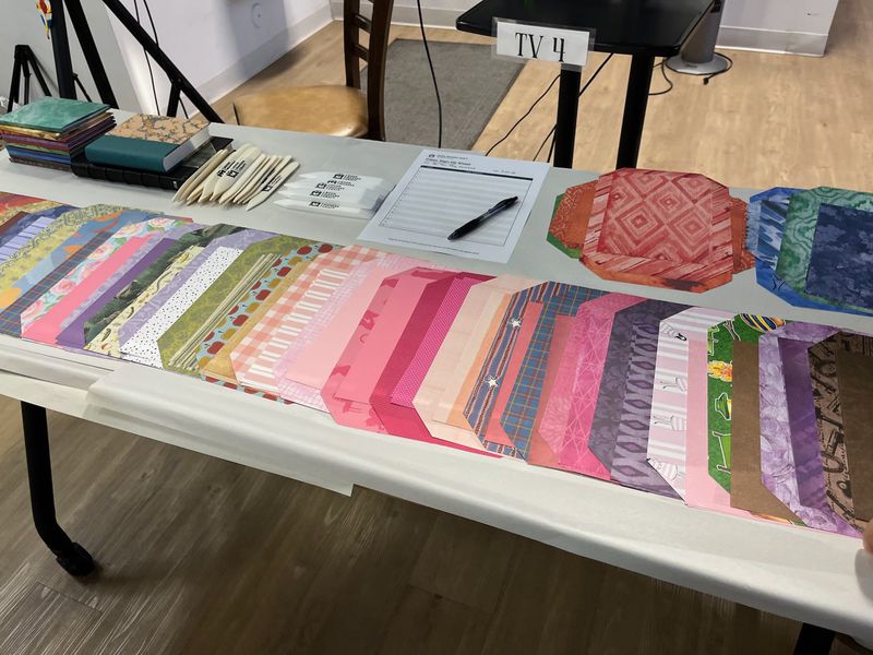 A table of decorative papers and cloth laid out for students to choose their covers.