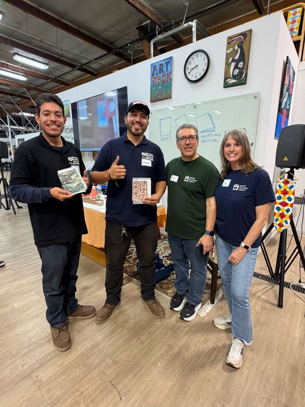 Bob with the Art Trek team, holding up finished notebooks after the class.